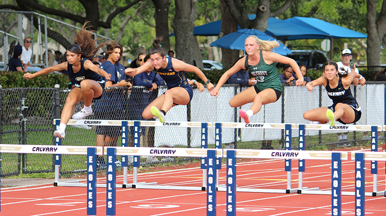 Athletes clearing hurdles during an outdoor track and field race